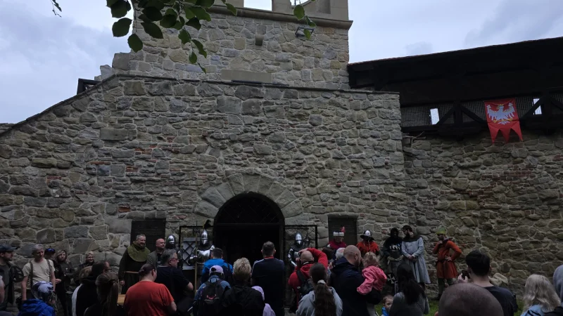 Uroczyste otwarcie Baszty Kowalskiej w Nowym Sączu. Na zdjęciu widoczna jest historyczna baszta z kamienia, przed którą zgromadziła się duża grupa ludzi na wydarzenie.